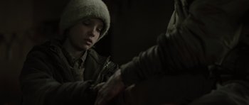 Movie still from “The Road” (2009), directed by John Hillcoat – A young person in a fur hat and jacket; Close Up shot, Over the shoulder angle