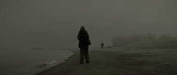 Movie still from “The Road” (2009), directed by John Hillcoat – Two people standing on a beach in the fog; Wide shot, Low angle