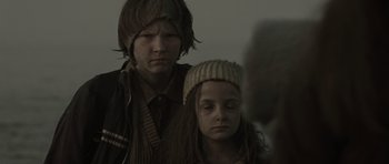 Movie still from “The Road” (2009), directed by John Hillcoat – Two young people are sitting next to each other; Close Up shot, Over the shoulder angle