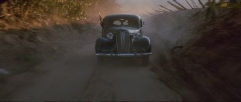 Movie still from “The Rocketeer” (1991), directed by Joe Johnston – An old car driving down a dirt road; Wide shot, High angle