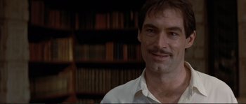 Movie still from “The Rocketeer” (1991), directed by Joe Johnston – A person wearing a white shirt in front of a book shelf; Close Up shot, Low angle