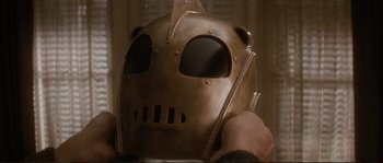 Movie still from “The Rocketeer” (1991), directed by Joe Johnston – A person wearing a metal helmet with a face mask on it; Close Up shot, Low angle