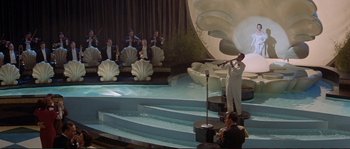 Movie still from “The Rocketeer” (1991), directed by Joe Johnston – A man is singing in front of an orchestra; Extreme Wide shot, High angle