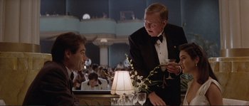 Movie still from “The Rocketeer” (1991), directed by Joe Johnston – A man in a tuxedo talking to another man in a suit; Medium shot, Over the shoulder angle