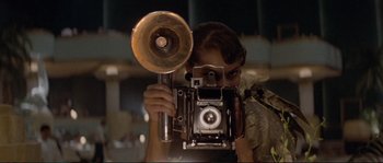 Movie still from “The Rocketeer” (1991), directed by Joe Johnston – A woman taking a picture with a camera; Close Up shot, Low angle