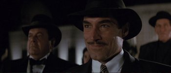 Movie still from “The Rocketeer” (1991), directed by Joe Johnston – A man wearing a suit and a hat; Close Up shot, Over the shoulder angle