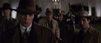 Movie still from “The Rocketeer” (1991), directed by Joe Johnston – A group of men in coats and hats are standing in a room; Medium shot, Low angle