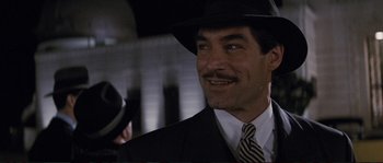 Movie still from “The Rocketeer” (1991), directed by Joe Johnston – A person wearing a suit and a hat; Close Up shot, Low angle