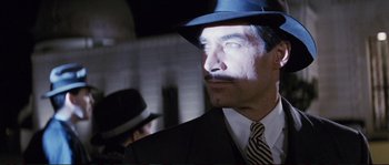 Movie still from “The Rocketeer” (1991), directed by Joe Johnston – A man in a suit and a hat is looking to his left; Close Up shot, Low angle