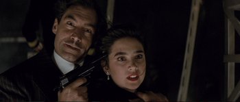 Movie still from “The Rocketeer” (1991), directed by Joe Johnston – A man and a woman holding guns in a dark room; Close Up shot, High angle