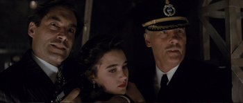 Movie still from “The Rocketeer” (1991), directed by Joe Johnston – A man and a woman standing next to each other in front of an officer; Close Up shot, Over the shoulder angle