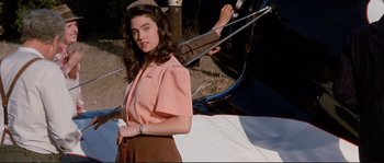 Movie still from “The Rocketeer” (1991), directed by Joe Johnston – A woman in a pink shirt and brown skirt; Medium shot, Low angle