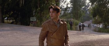 Movie still from “The Rocketeer” (1991), directed by Joe Johnston – A man in a brown jacket walking down a street; Medium shot, Over the shoulder angle