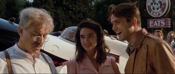 Movie still from “The Rocketeer” (1991), directed by Joe Johnston – A woman in a pink dress standing in front of an airplane; Close Up shot, Over the shoulder angle