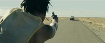 Movie still from “The Rover” (2014), directed by David Michôd – A person is pointing a gun at a car; Medium shot, Over the shoulder angle
