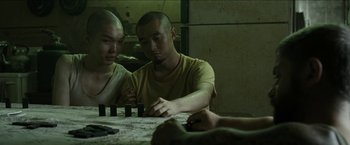 Movie still from “The Rover” (2014), directed by David Michôd – Two men sitting in front of a table; Medium shot, High angle