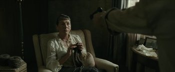 Movie still from “The Rover” (2014), directed by David Michôd – An older woman sitting in a chair knitting; Close Up shot, Over the shoulder angle