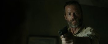 Movie still from “The Rover” (2014), directed by David Michôd – A person holding a gun; Close Up shot, Over the shoulder angle