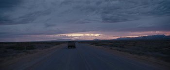 Movie still from “The Rover” (2014), directed by David Michôd – A car driving down the road at sunset; Extreme Wide shot, Over the shoulder angle