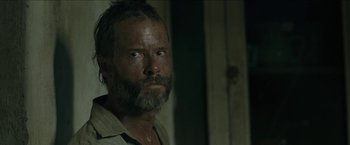 Movie still from “The Rover” (2014), directed by David Michôd – A person with a beard looking at the camera; Close Up shot, Over the shoulder angle