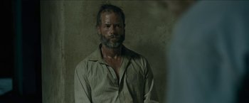 Movie still from “The Rover” (2014), directed by David Michôd – A man with a gray beard is looking at the camera; Close Up shot, Over the shoulder angle