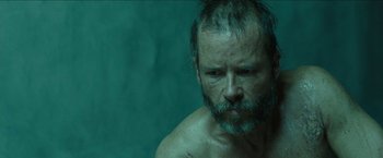 Movie still from “The Rover” (2014), directed by David Michôd – A man with a beard and a mustache is looking at the camera; Close Up shot, Over the shoulder angle