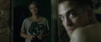Movie still from “The Rover” (2014), directed by David Michôd – A woman standing next to a man in front of a wall; Medium shot, Over the shoulder angle