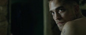 Movie still from “The Rover” (2014), directed by David Michôd – A man's face in a dark room; Close Up shot, High angle