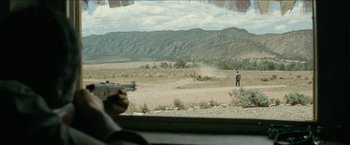 Movie still from “The Rover” (2014), directed by David Michôd – A man with a gun looking out of a car window; Extreme Wide shot, Over the shoulder angle