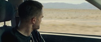 Movie still from “The Rover” (2014), directed by David Michôd – A person sitting in a car looking out the window; Close Up shot, Over the shoulder angle