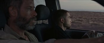 Movie still from “The Rover” (2014), directed by David Michôd – A man sitting in the back seat of a car; Medium shot, Over the shoulder angle