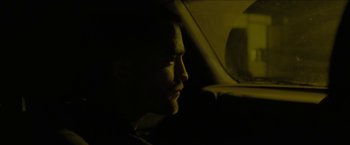 Movie still from “The Rover” (2014), directed by David Michôd – A man sitting in the back seat of a car looking out the window; Close Up shot, Over the shoulder angle