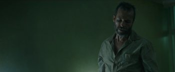 Movie still from “The Rover” (2014), directed by David Michôd – A man standing in front of a green wall; Close Up shot, Low angle