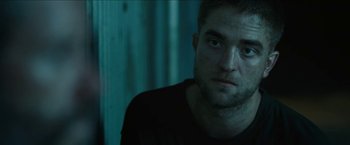 Movie still from “The Rover” (2014), directed by David Michôd – A person wearing a black t - shirt; Close Up shot, Over the shoulder angle