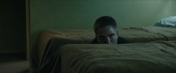 Movie still from “The Rover” (2014), directed by David Michôd – A man hiding behind a couch in a living room; Medium shot, High angle