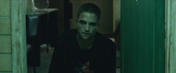 Movie still from “The Rover” (2014), directed by David Michôd – A person sitting in a room; Medium shot, High angle