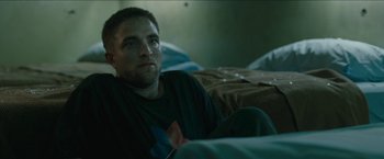 Movie still from “The Rover” (2014), directed by David Michôd – A person laying on a bed; Medium shot, High angle