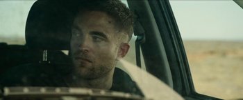 Movie still from “The Rover” (2014), directed by David Michôd – A person sitting in a car; Close Up shot, Over the shoulder angle