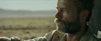 Movie still from “The Rover” (2014), directed by David Michôd – A person with a beard; Close Up shot, Over the shoulder angle