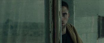Movie still from “The Rover” (2014), directed by David Michôd – A person leaning against a window sill; Close Up shot, Over the shoulder angle