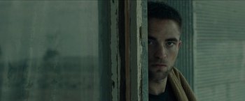 Movie still from “The Rover” (2014), directed by David Michôd – A person looking out of a window; Close Up shot, Low angle