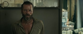 Movie still from “The Rover” (2014), directed by David Michôd – A person wearing a shirt and looking at the camera; Close Up shot, Over the shoulder angle
