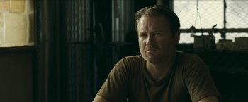 Movie still from “The Rover” (2014), directed by David Michôd – A person sitting in a room; Close Up shot, Over the shoulder angle