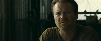 Movie still from “The Rover” (2014), directed by David Michôd – A person sitting down; Close Up shot, Over the shoulder angle