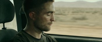 Movie still from “The Rover” (2014), directed by David Michôd – A person sitting in a car looking out the window; Close Up shot, High angle