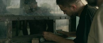 Movie still from “The Rover” (2014), directed by David Michôd – A man is putting money in an oven; Medium shot, Low angle