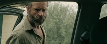 Movie still from “The Rover” (2014), directed by David Michôd – A man with a long beard looking out of a car window; Close Up shot, Over the shoulder angle