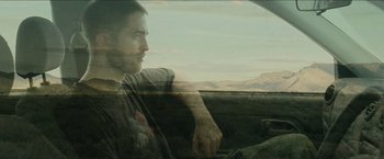 Movie still from “The Rover” (2014), directed by David Michôd – A man sitting in the driver's seat of a car; Medium shot, Low angle