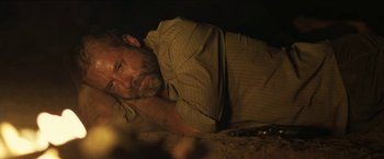 Movie still from “The Rover” (2014), directed by David Michôd – A man laying on the ground in the dark; Close Up shot, High angle