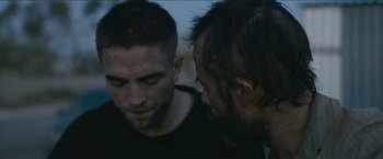 Movie still from “The Rover” (2014), directed by David Michôd – Two men talking to each other in the dark; Close Up shot, Over the shoulder angle